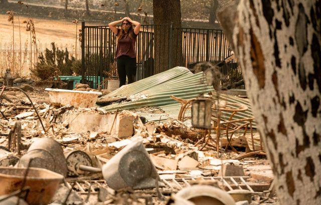 Alyssa Medina looks over the charred remains of her family home during the LNU Lightning Complex fire in Vacaville, CA.