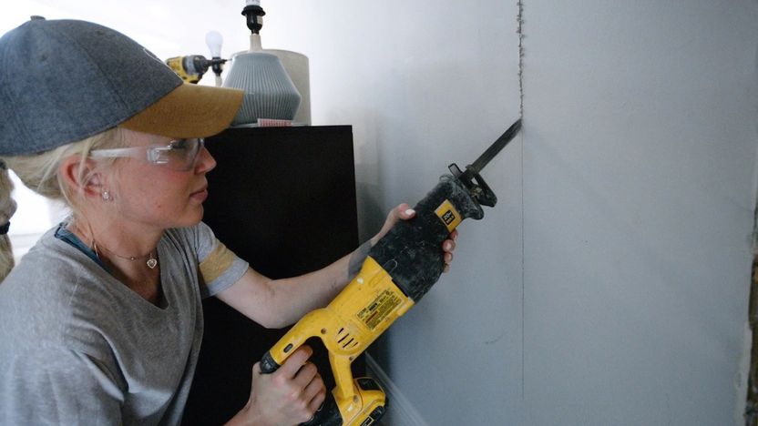 Galey Alix cuts into drywall during a weekend renovation.
