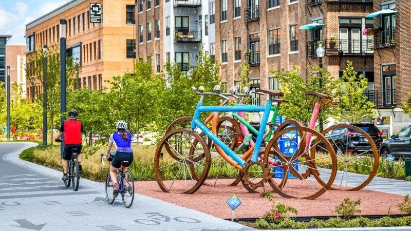Two people pass by a sculpture of giant bikes in the city center of Carmel, IN